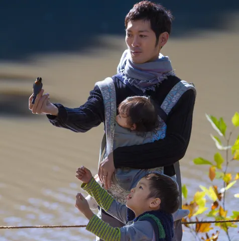 Father feeds a bird while his kids look on, Meiji Garden